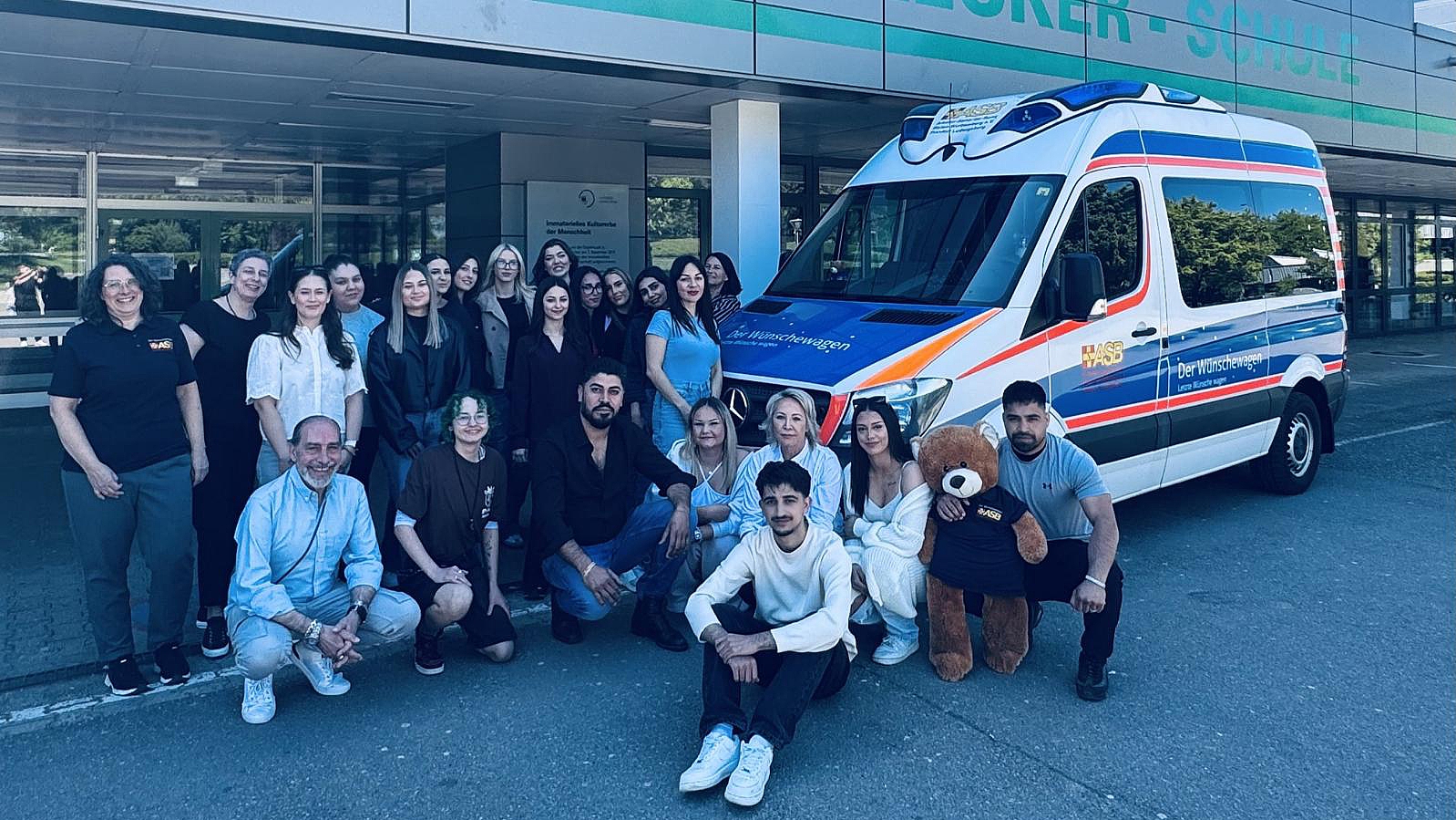 Gruppe von Auszubildenden vor der Oscar-Walcker-Schule neben einem Wünschewagen-Fahrzeug des ASB im Rahmen einer Spendenaktion.