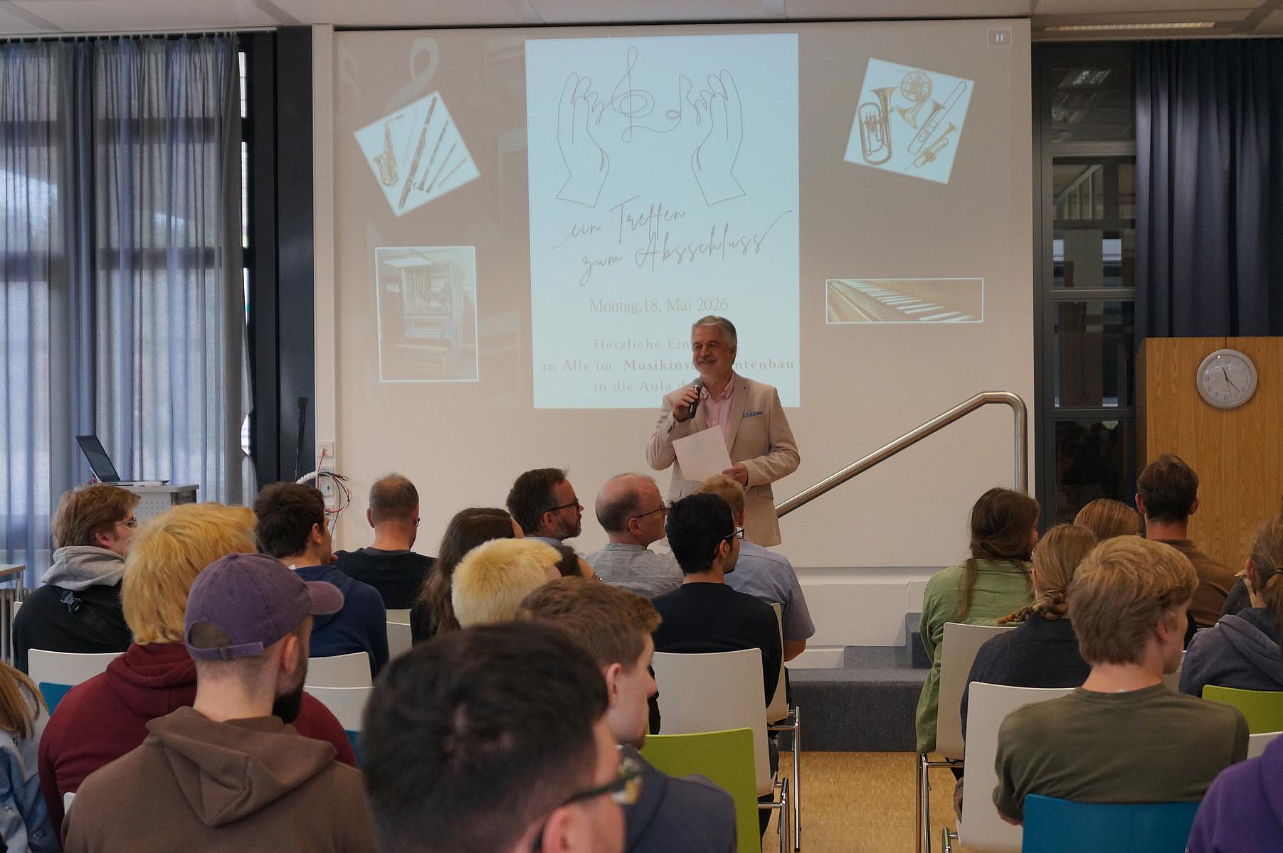 Ansprache des Abteilungsleiters in der Aula der Oscar-Walker-Schule vor Publikum während der feierlichen Verabschiedung des Gesellenjahrgangs.